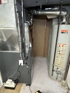 A furnace and water heater in a utility area, showcasing HVAC and plumbing components by Family First Heating and Cooling Repair LLC in Toledo, OH.