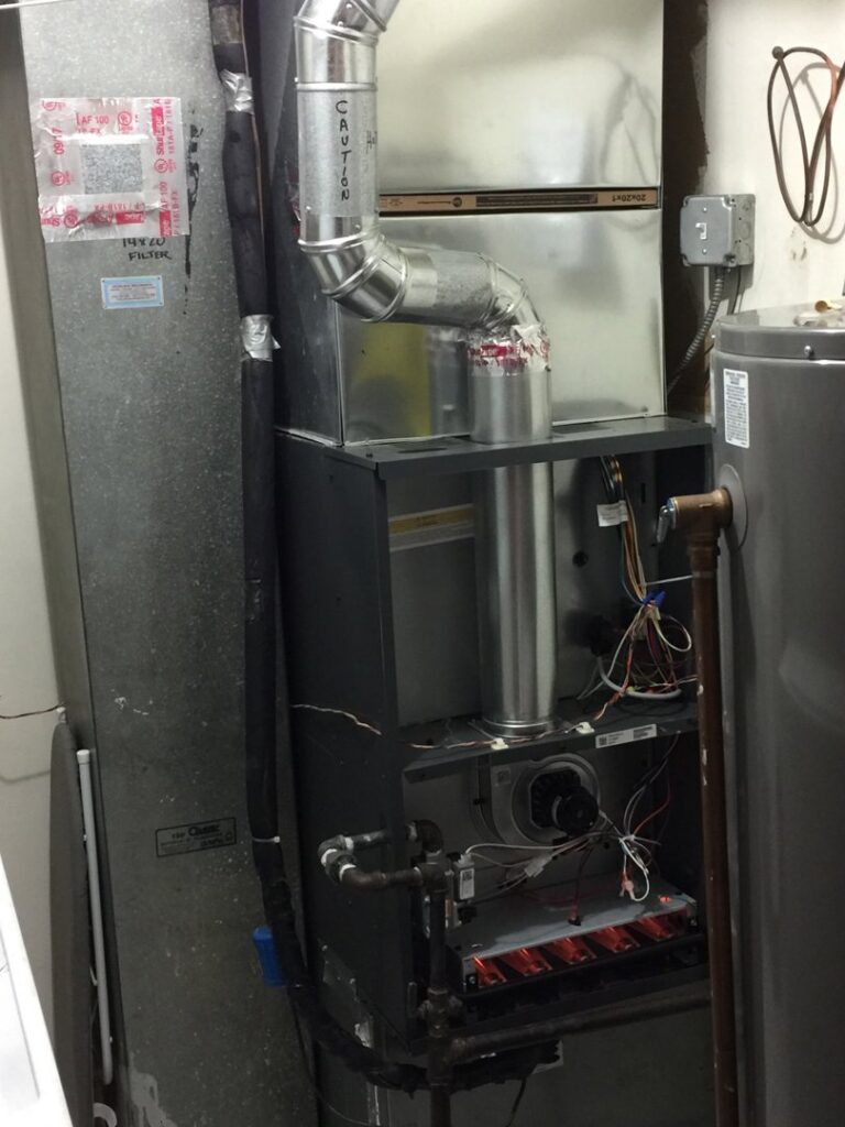 An open furnace with its cover removed, showing internal components and flames during a service call by Around The Town Heating and Cooling in Chicago, IL.