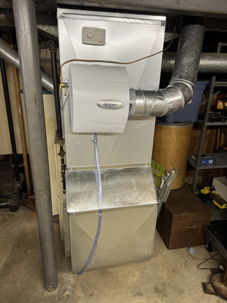 A furnace unit with an Aprilaire humidifier installed, connected to ductwork by Lopez Mechanical HVAC in Kansas City, MO.