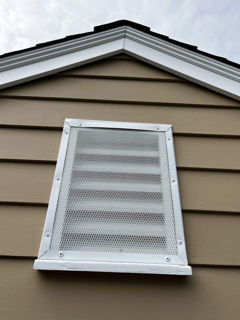 A metal mesh screen installed over a gable vent to prevent wildlife entry by Defense Pest and Wildlife Control in Hartford, CT.