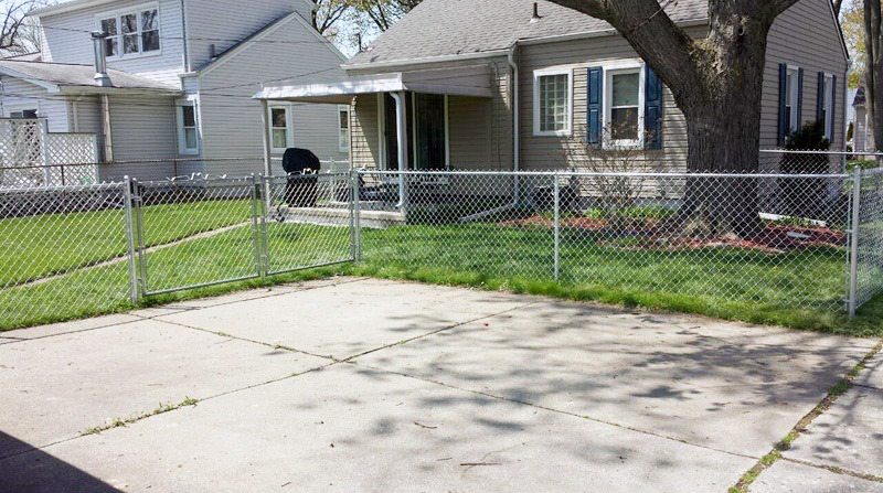 A galvanized chain-link fence with a gate installed in a front yard by Fence Masters Upstate SC in Greenville, SC
