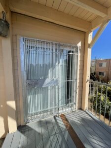 A galvanized metal security door with vertical bars installed on a balcony by Fierro Iron Works Inc. in San Francisco, CA.
