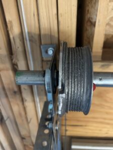 A close-up of a garage door cable drum and track system, inspected by SS Garage Door Repair in Denver, CO.