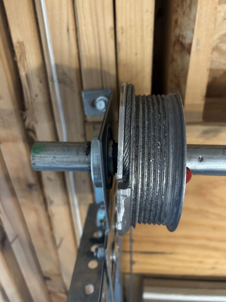 A close-up of a garage door cable drum and track system, inspected by SS Garage Door Repair in Denver, CO.
