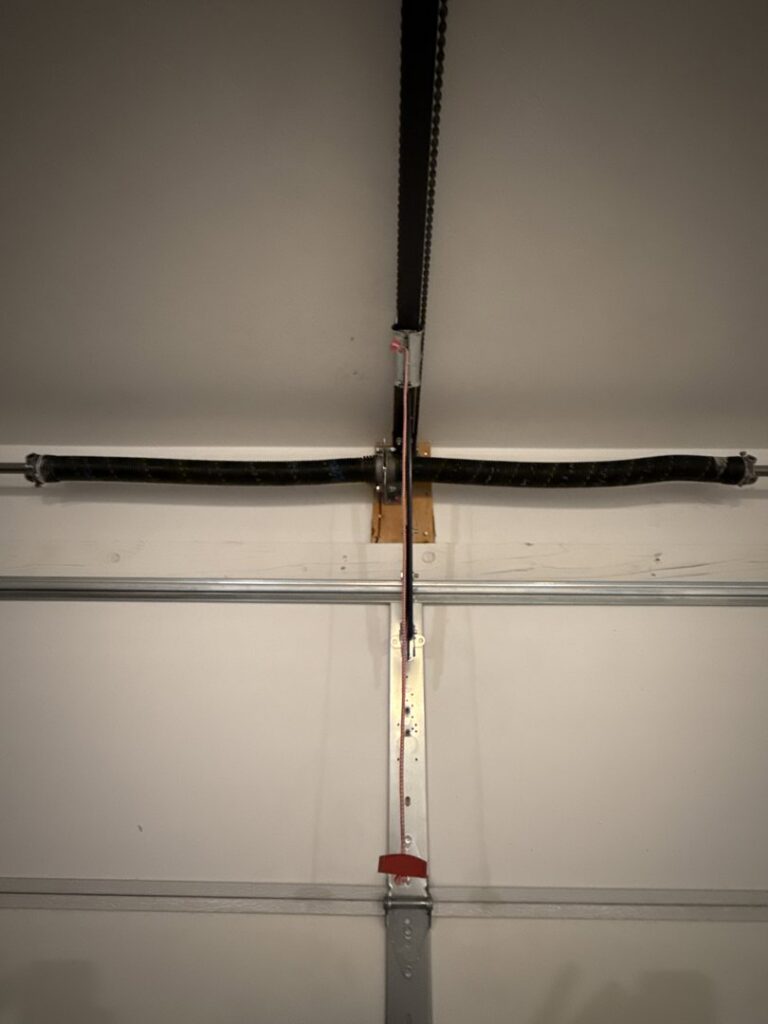 A close-up of a garage door chain drive and torsion springs, showing components serviced by Tucson Garage Door Doc in Tucson, AZ.