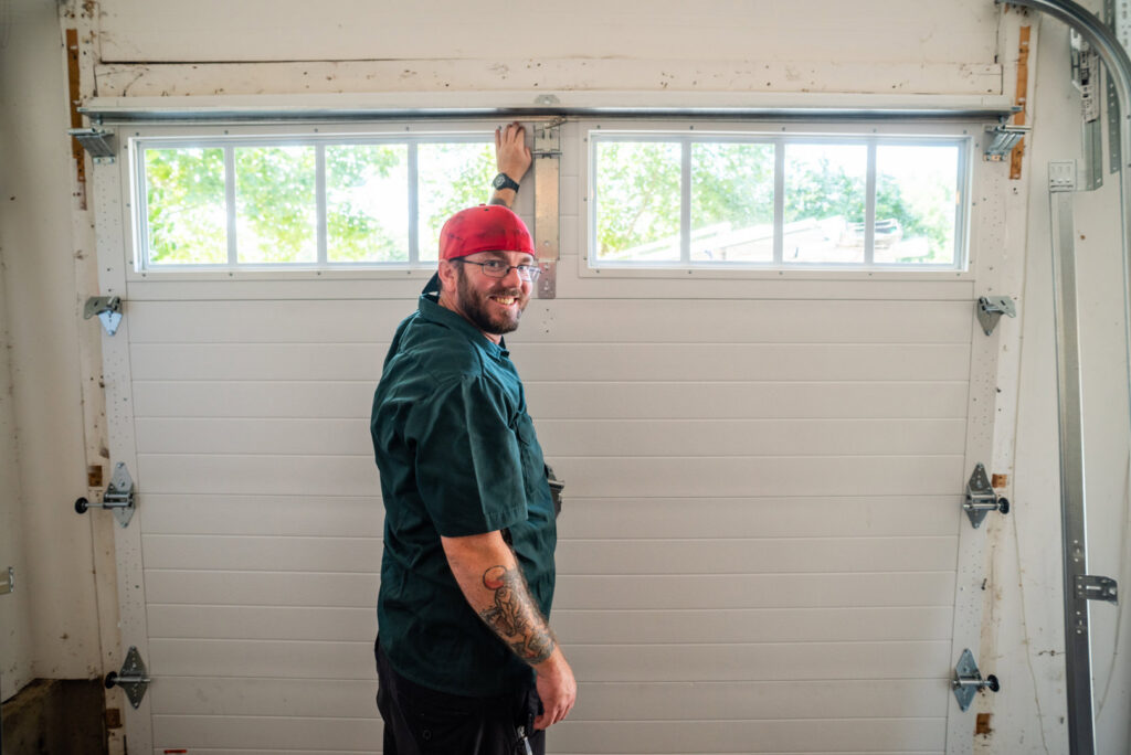 The Annapolis Garage Doors Inc. team posing with a new garage door panel during an installation job in Annapolis, MD.