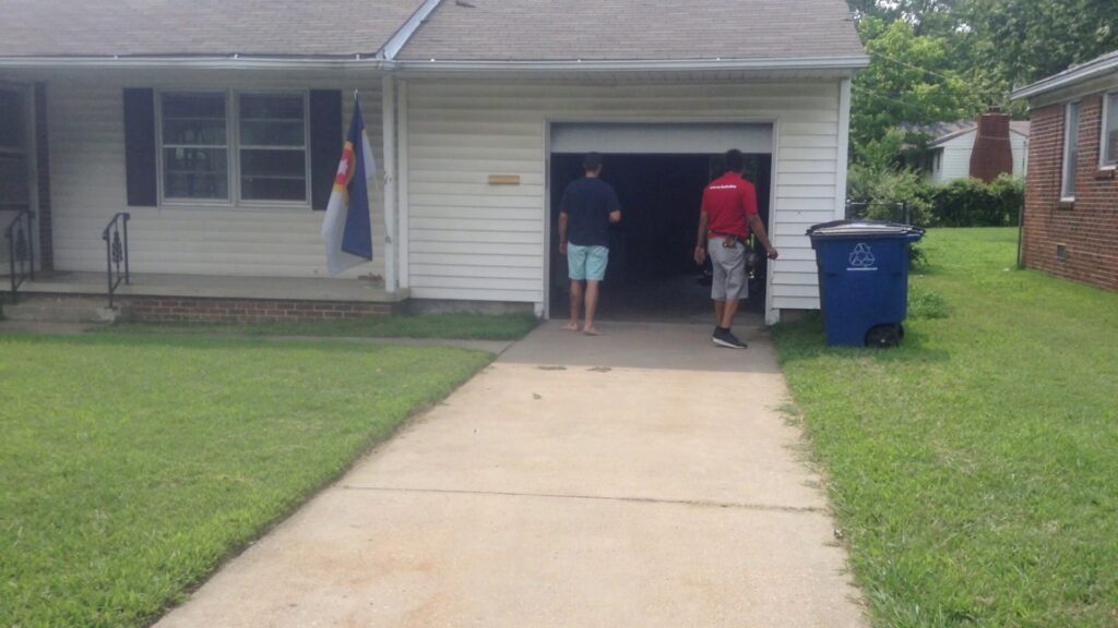 Two garage door contractors on site at a residential job, standing in front of an open garage door for OklaHome Overhead Doors in Tulsa, OK