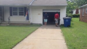 Two garage door contractors on site at a residential job, standing in front of an open garage door for OklaHome Overhead Doors in Tulsa, OK