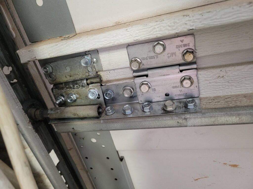 Close-up of garage door hinges and rollers on the track, showing components for repair by Gryffin Garage Door in Chandler, AZ