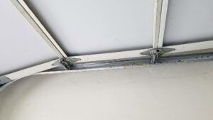 A close-up view of garage door hinges and tracks from the interior, showing repair work by Johns Garage Doors in Tucson, AZ.