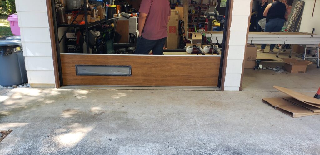 A brown garage door with a window panel being installed by Coast To Coast Garage Door LLC in Vancouver, WA.