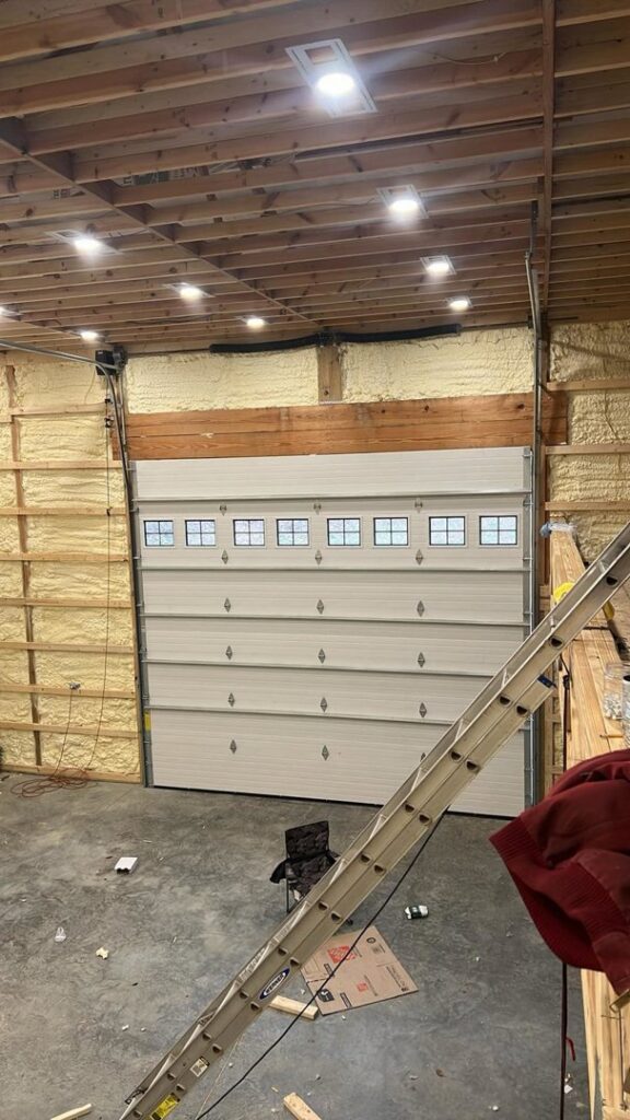 A white garage door being installed in a wooden framed structure, showcasing a job in progress by Honest Overhead Garage Doors in Elizabethtown, KY.