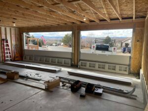 Interior view of a garage with two garage doors in progress of installation, showing components on the floor by PNG Garage Doors llc in Lakewood, CO.