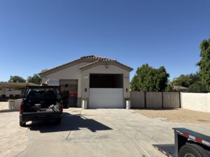 An exterior view of a house with a garage door installation in progress, with a service truck and lift from MGG Garage Door Service in San Tan Valley, AZ