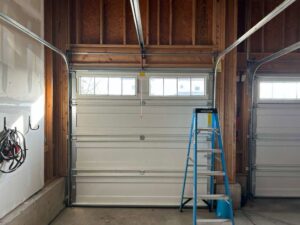 A garage interior showing a white garage door installation in progress with a ladder, by SS Garage Door Repair in Denver, CO.
