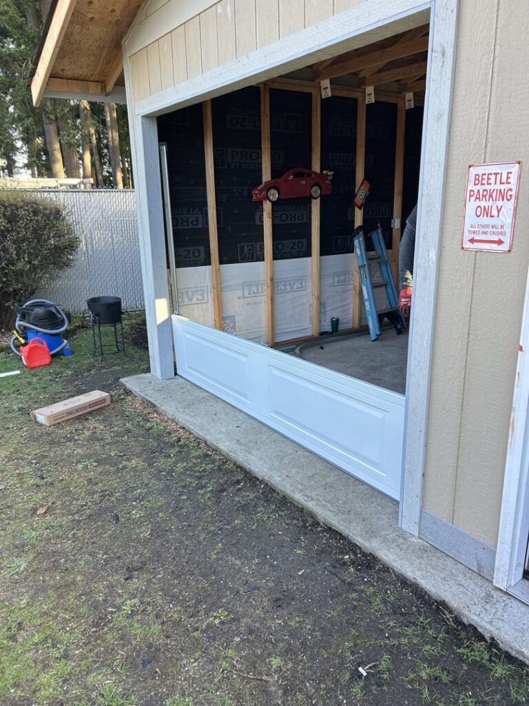 A garage door installation in progress, showing the bottom panel being fitted by Steadfast Garage Door Services LLC in Federal Way, WA.