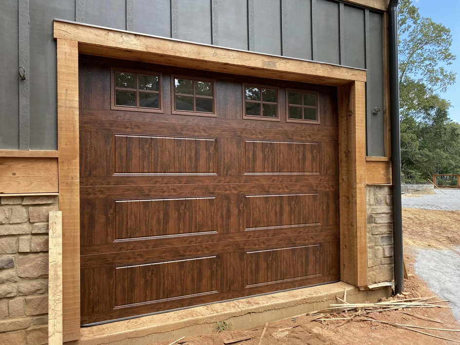 A brown garage door with windows installed in a new construction project by Mike's Garage Door Repair in Wetumpka, AL.