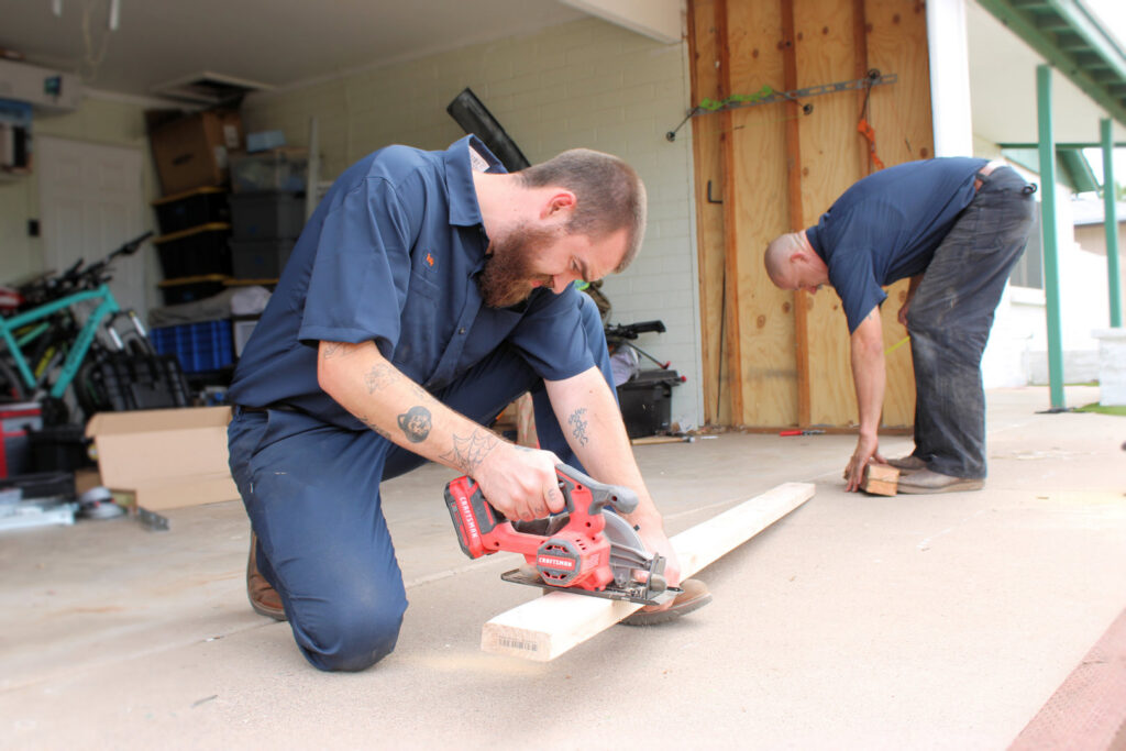 4 Sons Garage Door contractors preparing for a garage door installation, cutting wood in Phoenix, AZ.