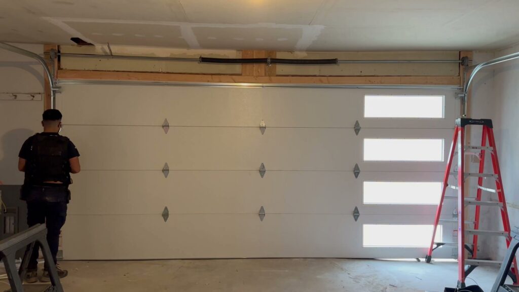 A worker installing or repairing a garage door from the inside, showcasing Strongdoor garage's service in Denver, CO.