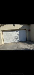 A garage door that is off its tracks and partially open, requiring repair from Olympus Garage Door Repair in Tempe, AZ.
