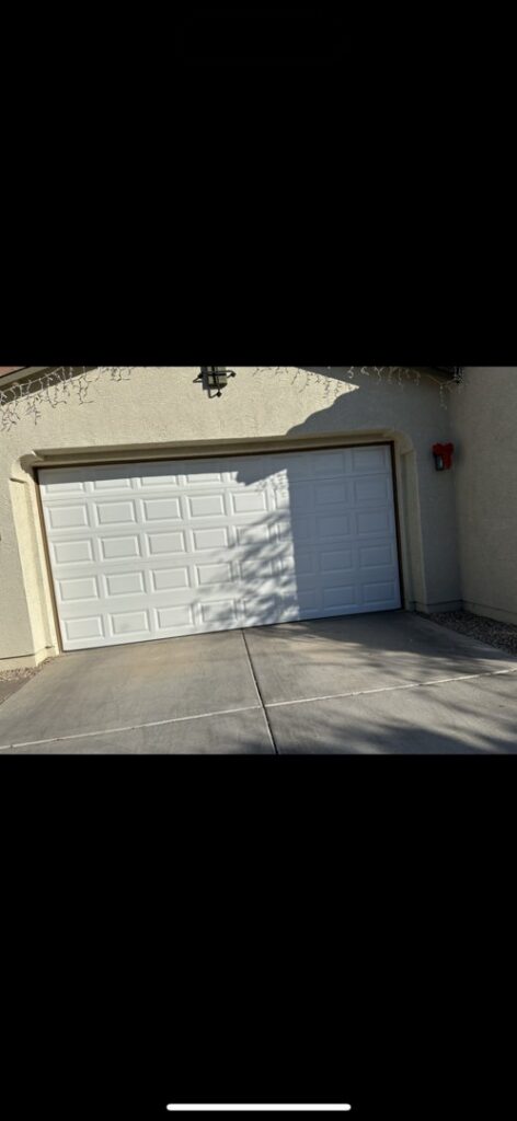 A garage door that is off its tracks and partially open, requiring repair from Olympus Garage Door Repair in Tempe, AZ.