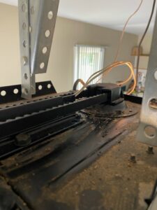 A close-up of a garage door opener belt drive and wiring, showing a component for repair by Foothills Garage Door Service LLC in Louisville, TN.