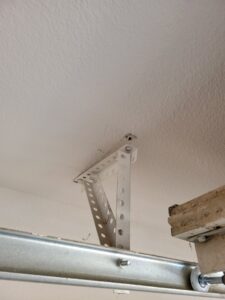 A garage door opener mounting bracket installed on the ceiling, part of a service by Gryffin Garage Door in Chandler, AZ