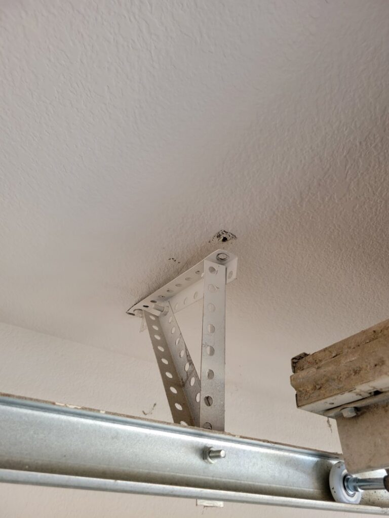 A garage door opener mounting bracket installed on the ceiling, part of a service by Gryffin Garage Door in Chandler, AZ