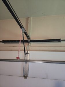 A close-up of a garage door opener's chain drive and spring mechanism, serviced by Overhead Door Company of Evansville in Evansville, IN.