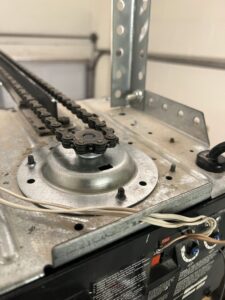 A close-up of a garage door opener's chain drive sprocket, showing components serviced by Tucson Garage Door Doc in Tucson, AZ.