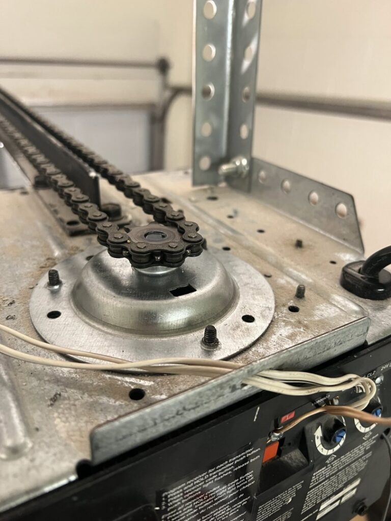A close-up of a garage door opener's chain drive sprocket, showing components serviced by Tucson Garage Door Doc in Tucson, AZ.