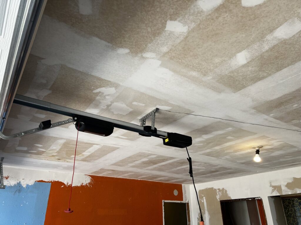 A garage door opener system professionally installed on the ceiling of a garage by Rhino Garage Doors LLC OKC in Edmond, OK.
