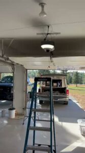 An interior view of a garage with a new garage door opener installed, showing a work site by SS Garage Door Repair in Denver, CO.