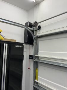 A close-up view of a garage door opener motor and track system, installed by Precision Garage Door of Charleston in North Charleston, SC.