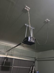 A garage door opener installation with visible wiring on a ceiling by Team Garage Doors in Mesa, AZ.