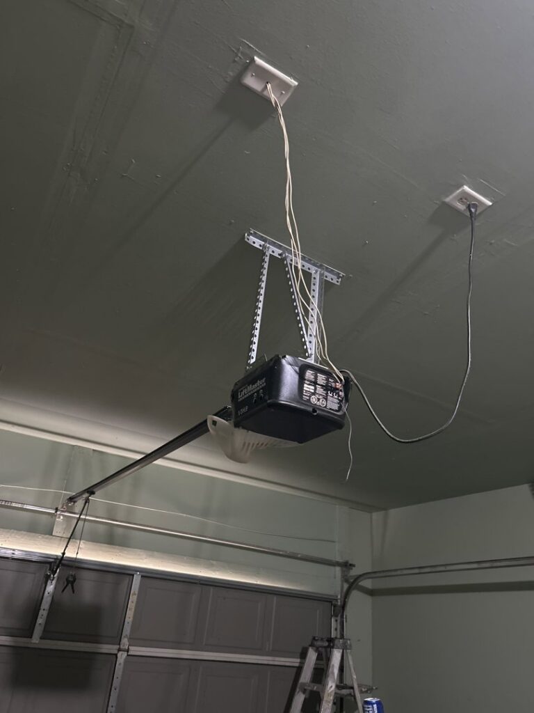 A garage door opener installation with visible wiring on a ceiling by Team Garage Doors in Mesa, AZ.