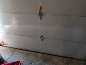 Close-up of garage door panels and hinges, indicating potential repair or maintenance work by Garage Doors & Remodeling LLC in Blue Springs, MO