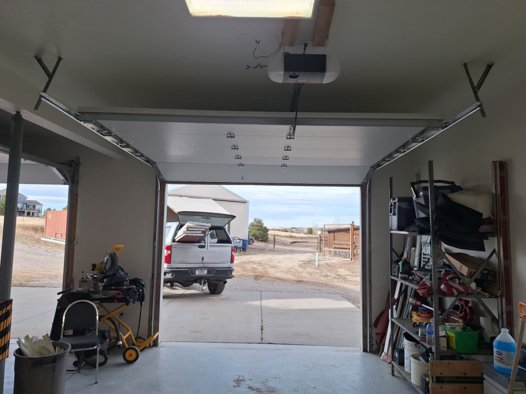 A garage door partially open, showing the opener and tracks, installed by Roll-Rite Garage Doors in Denver, CO.