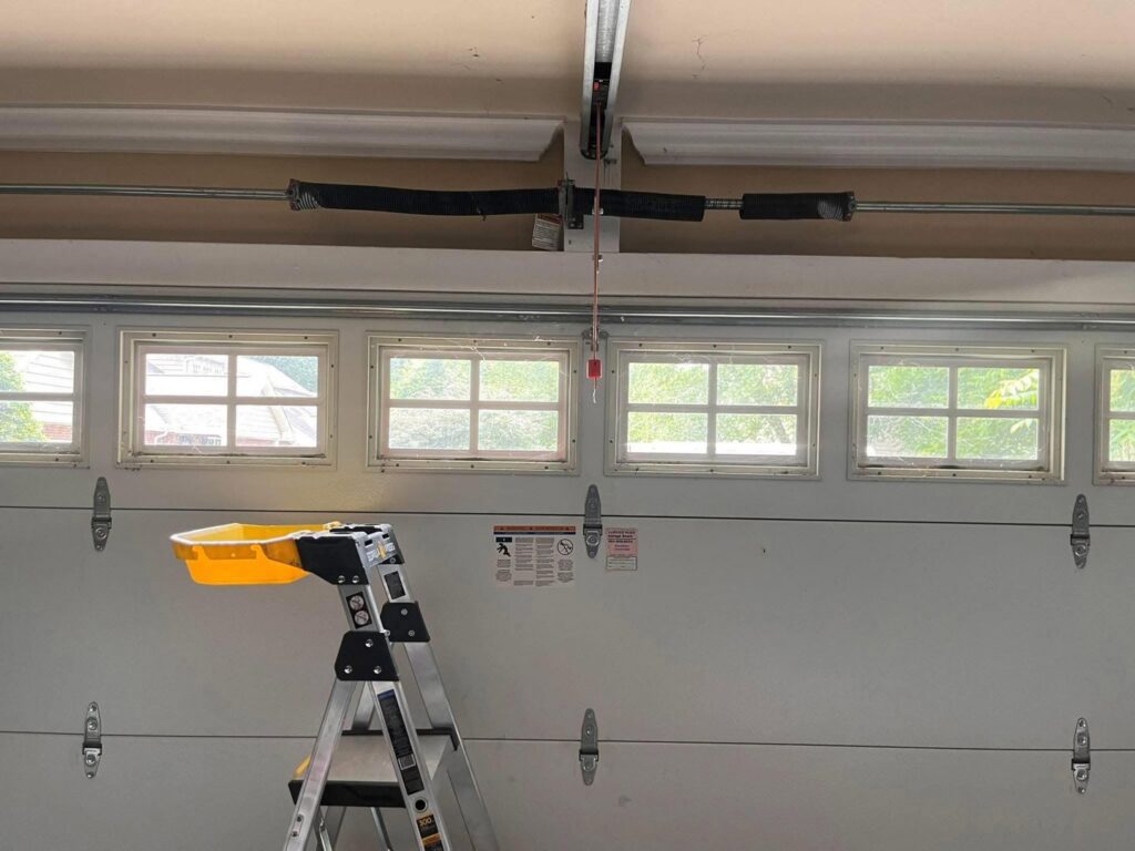Interior view of a garage door with a ladder and visible springs, indicating repair or maintenance in progress by Knox Garage Door Service LLC in Knoxville, TN.