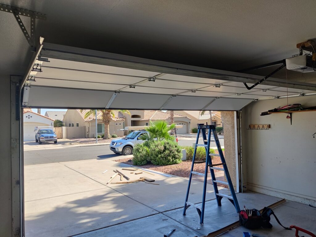 Garage door repair or installation in progress with a ladder and tools inside a garage by Absolute Garage Doors LLC AZ in Mesa, AZ