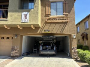 A garage door repair job site with an open garage door, a car, and a ladder, indicating service by 101 Garage Doors in Phoenix, AZ.
