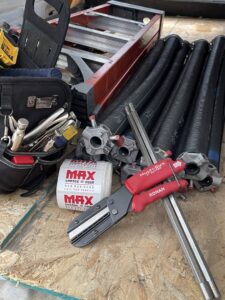 Various garage door repair tools, springs, and Max Garage Door stickers laid out for a job in Minneapolis, MN.