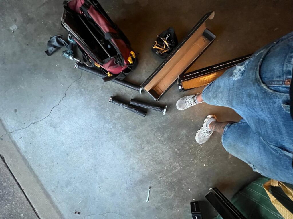 Tools and garage door parts laid out on the ground during a repair job by Lenny's Garage Door in Louisville, KY.