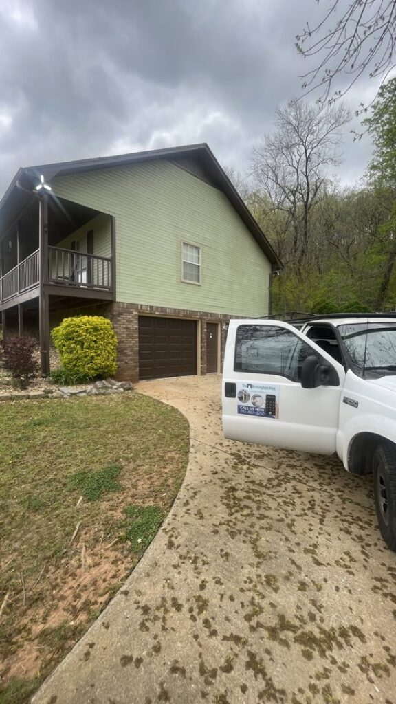 The Birmingham Man Garage Doors service truck parked at a home with a brown garage door, ready for repair in Birmingham, AL.