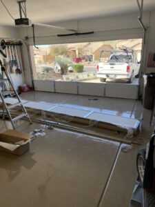 New garage door panels ready for installation with a service truck outside, showing a replacement job by MGG Garage Door Service in San Tan Valley, AZ