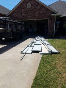 Garage door replacement in progress with panels on the driveway by Garage Door Specialists Of Oklahoma Inc. in Oklahoma City, OK