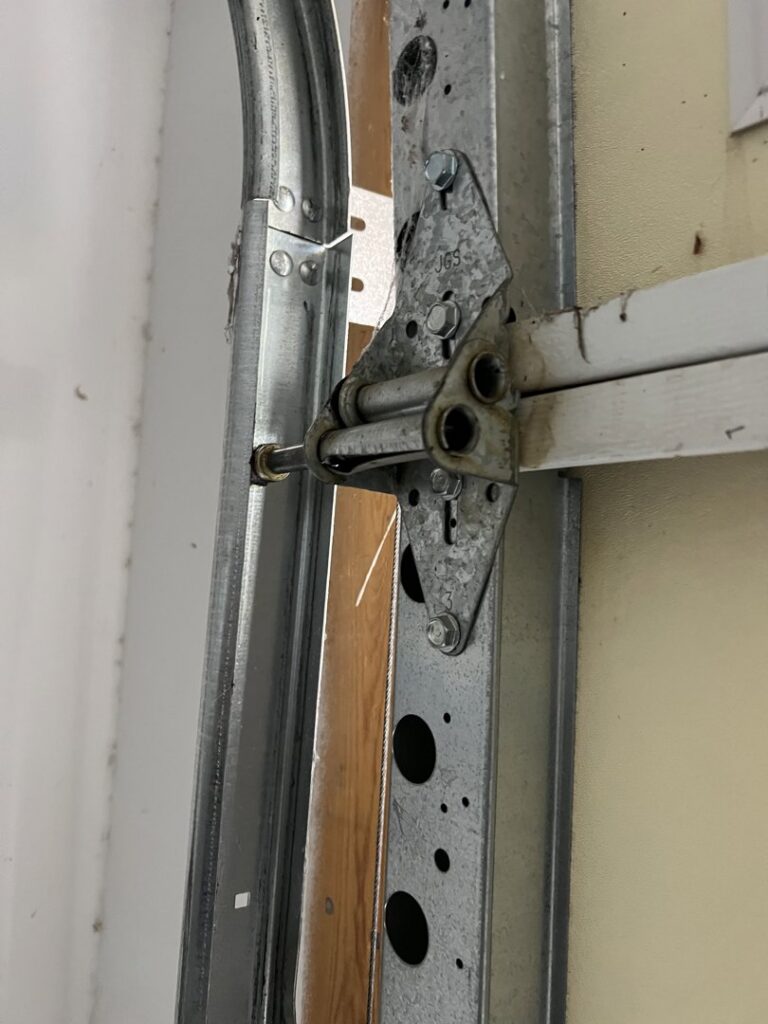 A close-up of a garage door roller and hinge on the track, showing components serviced by Tucson Garage Door Doc in Tucson, AZ.