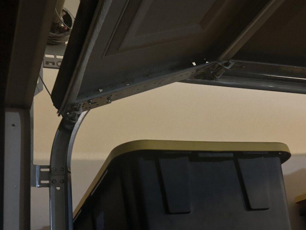 A close-up of a garage door roller off its track, showing a repair need for Olympus Garage Door Repair in Tempe, AZ.