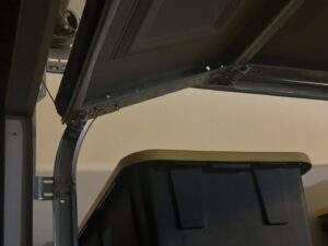 A close-up of a garage door roller off its track, showing a repair need for Olympus Garage Door Repair in Tempe, AZ.