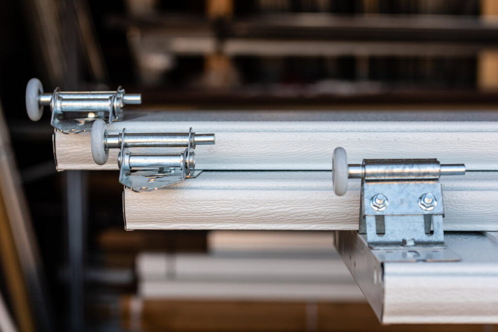 A close-up view of new garage door rollers and hinges on panels, representing parts used by Above The Rest Garage Door in Colorado Springs, CO.